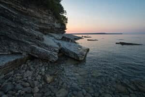 A coastline next to a rocky shore in the sunset